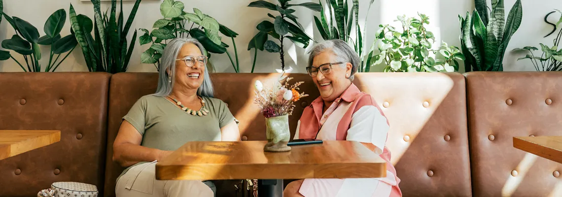 Two older women smiling while sitting in a restaurant booth