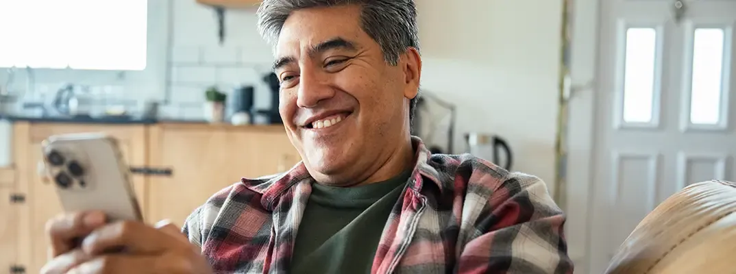 A smiling man looking at his phone