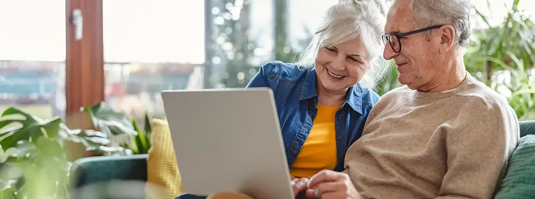 An older woman and older man working together on a laptop.