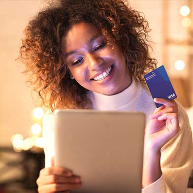 Woman holding a Sunward credit card while shopping online from her festive home